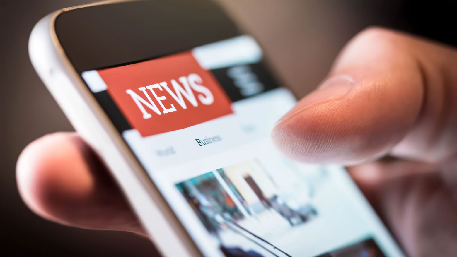 Nahaufnahme einer Hand, die ein Smartphone hält, auf dem eine Nachrichten-Website angezeigt wird.